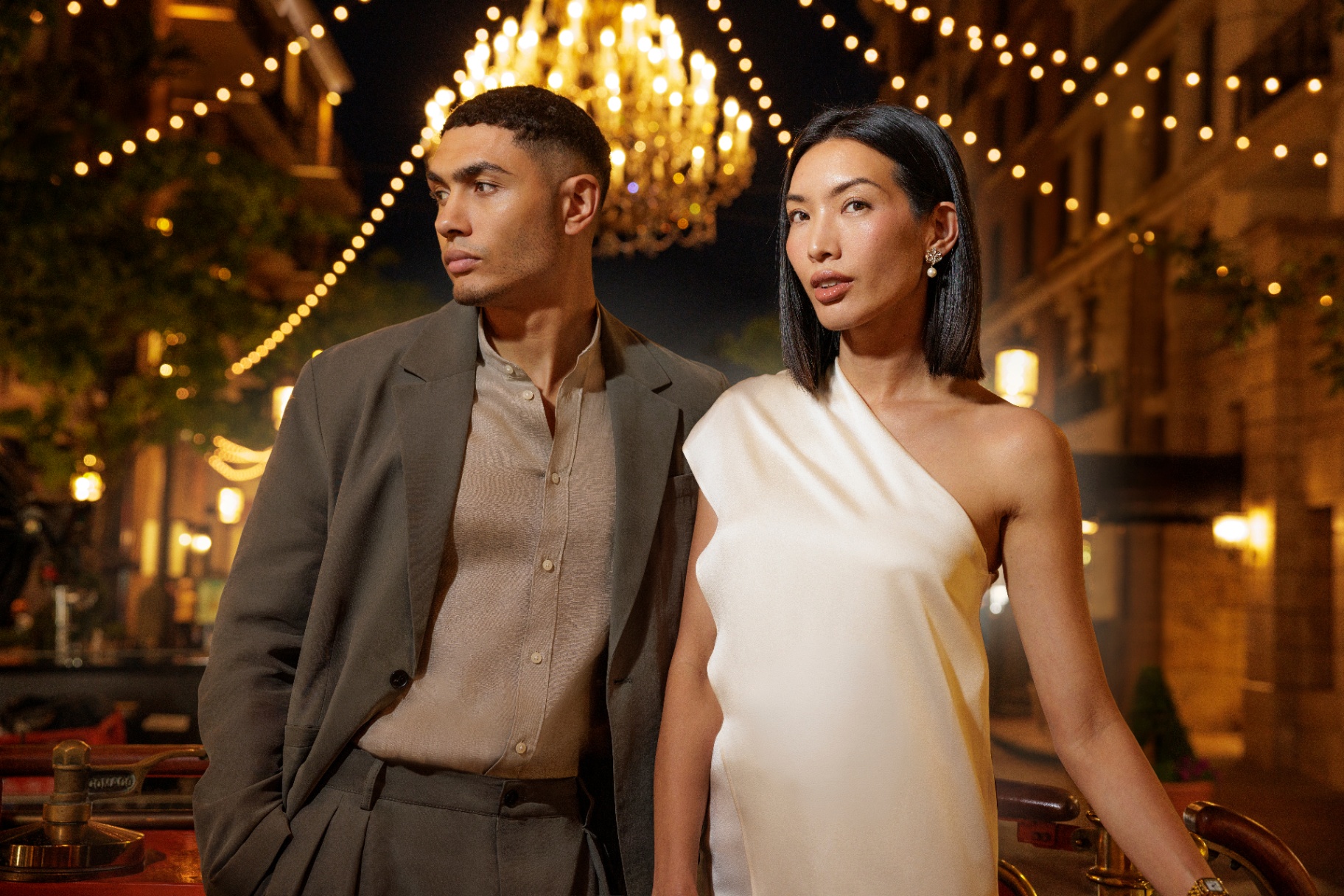 Couple in evening wear under string lights and chandelier
